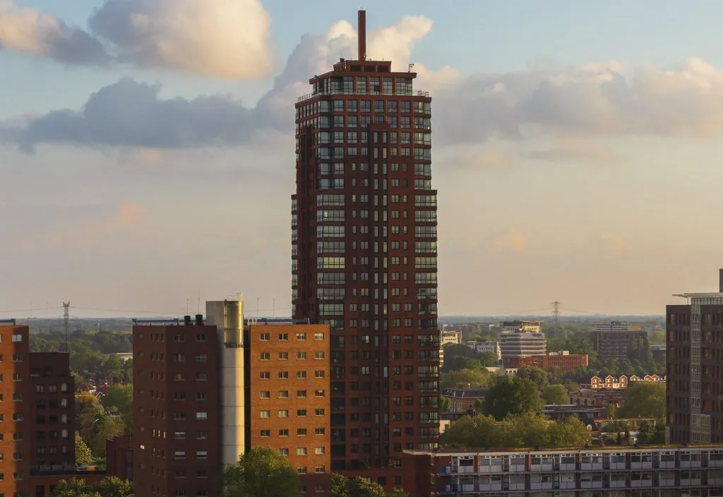 De Alphatower in Enschede tijdens zonsondergang, uitstekend boven de omliggende bebouwing.